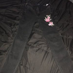 Black jeans with pink rose in the top left corner.